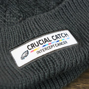 The Crucial Catch Eagles Logo on the Women's Philadelphia Eagles On Field NFL Crucial Catch Intercept Cancer Patch Rainbow Pom Pom Winter Beanie | Graphite Gray Winter Beanie