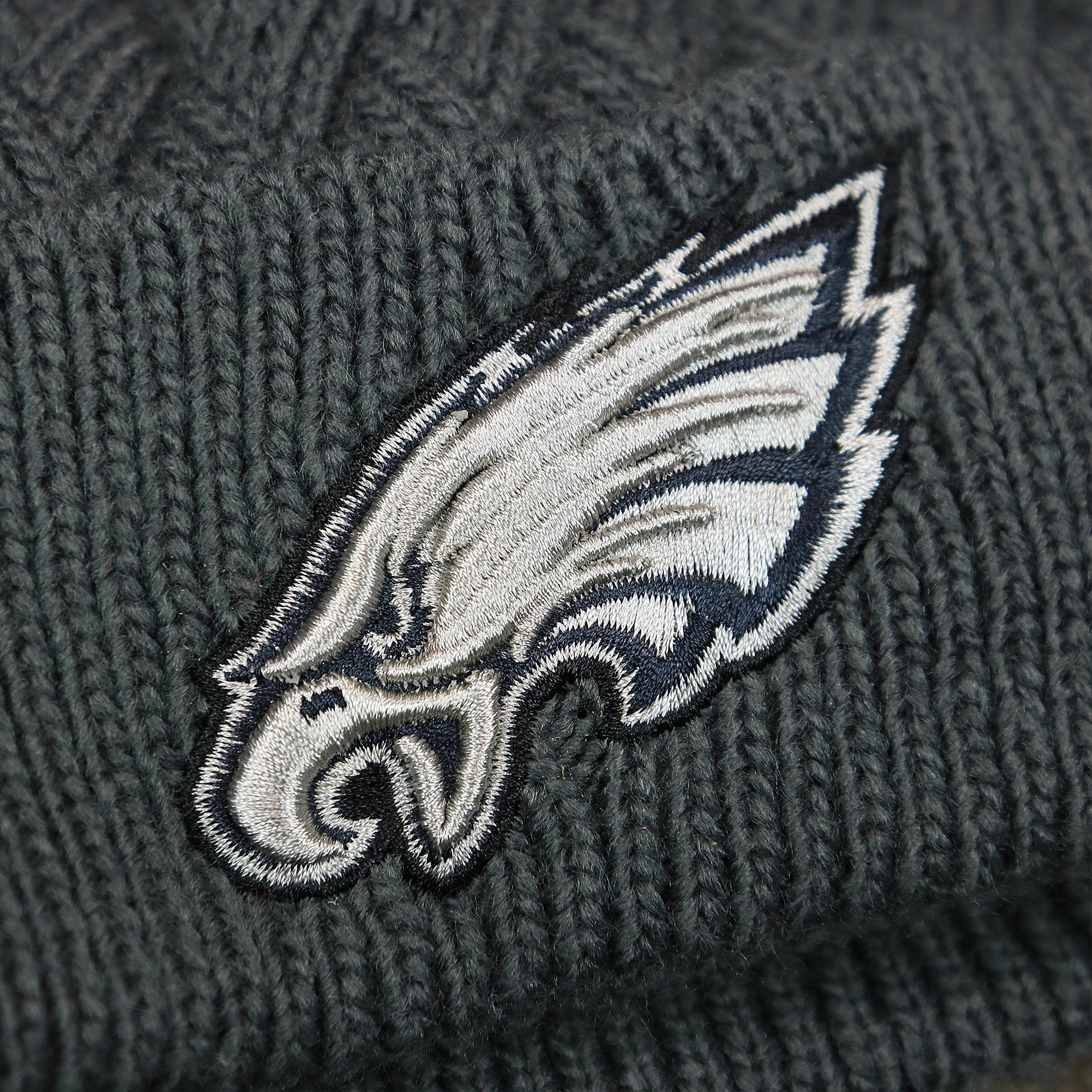 The Eagles Logo on the Women's Philadelphia Eagles On Field NFL Crucial Catch Intercept Cancer Patch Rainbow Pom Pom Winter Beanie | Graphite Gray Winter Beanie