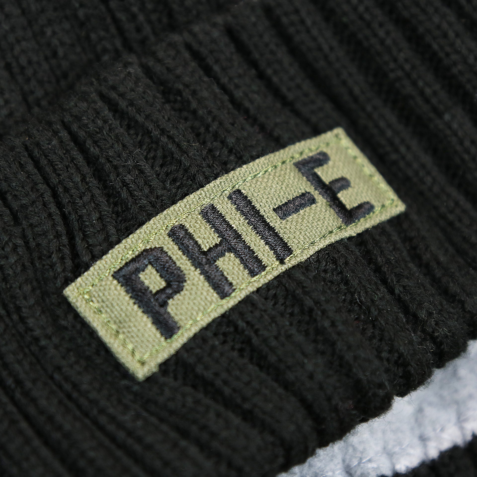 The Philadelphia Abbreviated Wordmark on the Philadelphia Eagles Salute To Service On Field Cuffed Winter Beanie | Black Winter Beanie