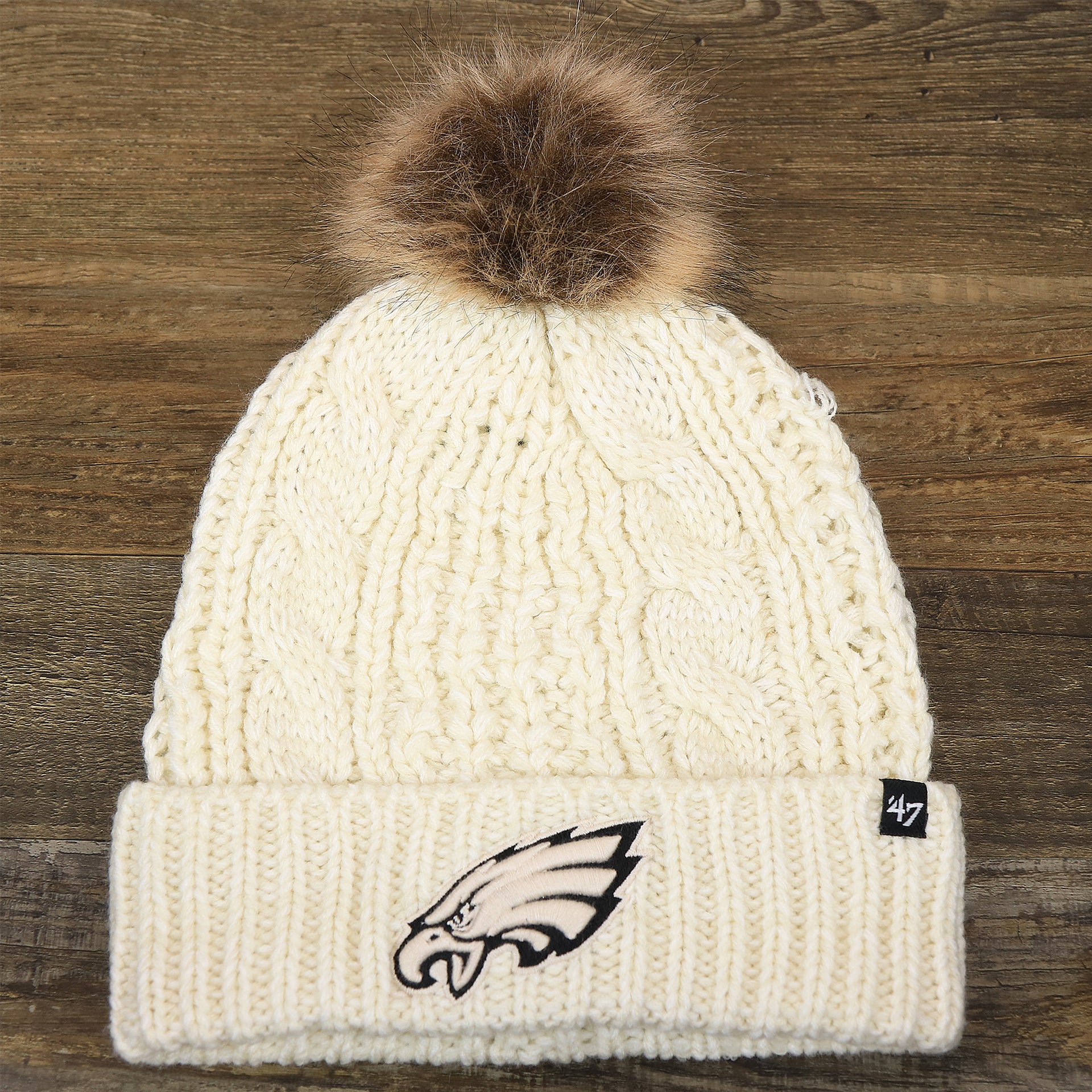 The front of the Women’s Philadelphia Eagles Cuffed Winter Knit Beanie With Meeko Pom Pom | Women’s Cream Winter Beanie