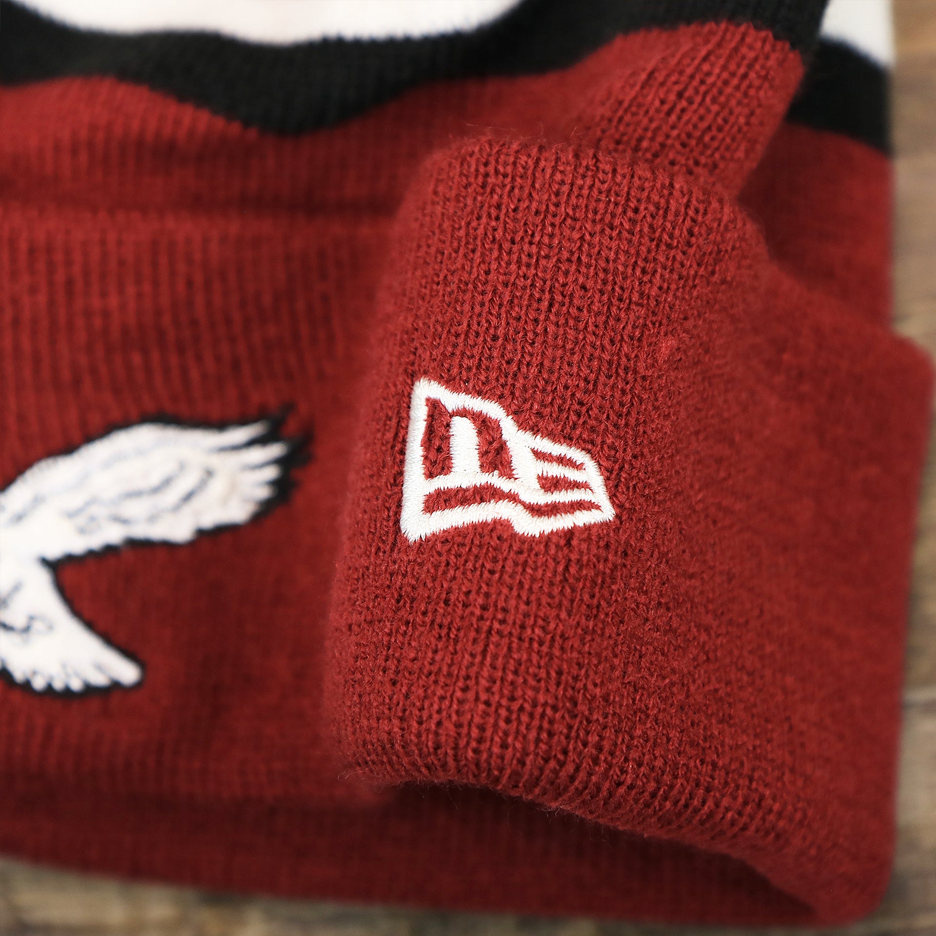 The New Era Logo on the Throwback Philadelphia Eagles White Logo Striped Cuffed Winter Beanie | Maroon Winter Beanie