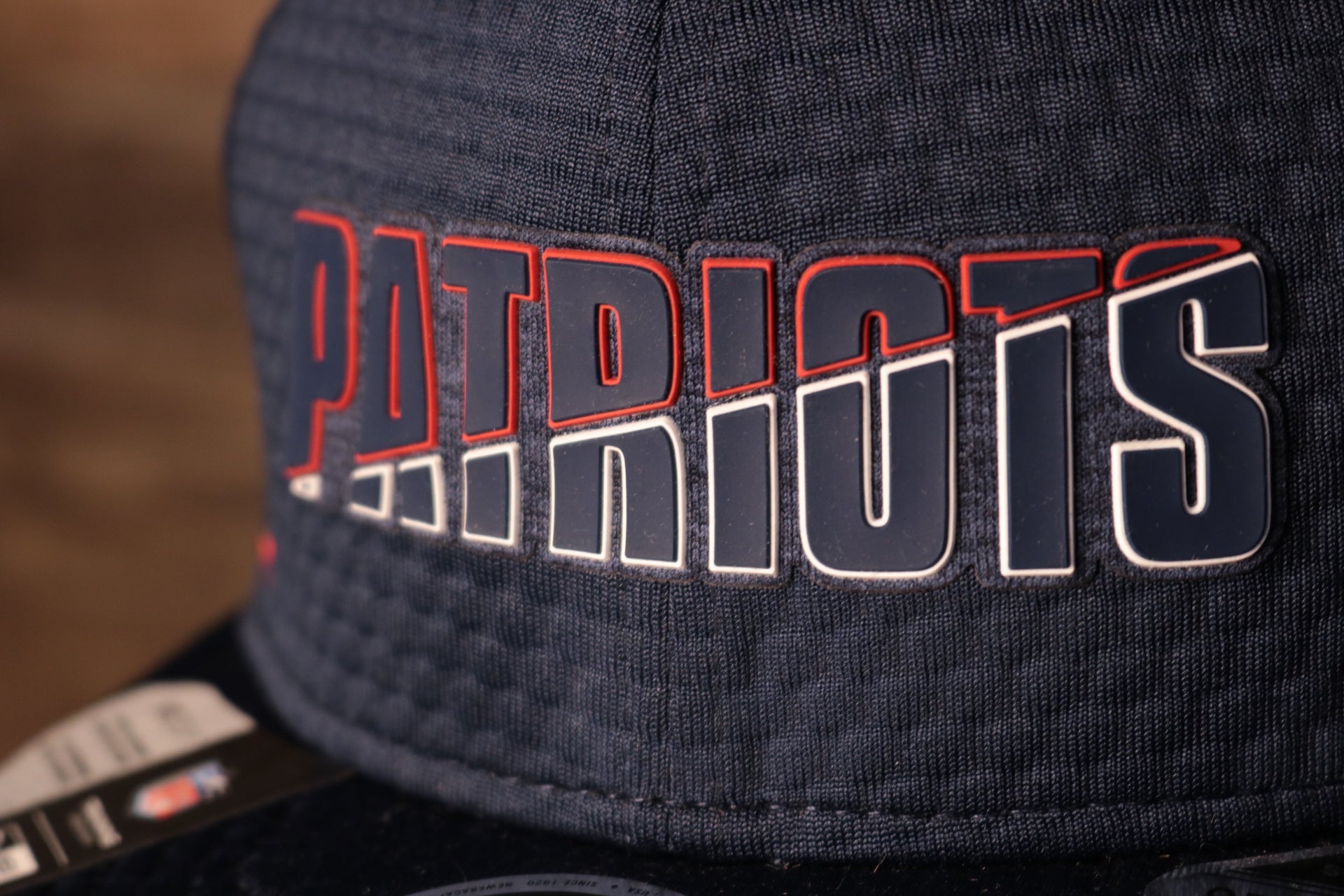 The patriots name is navy with a white and red outline Patriots 2020 Training Camp Snapback Hat | New England Patriots 2020 On-Field Navy Training Camp Snap Cap