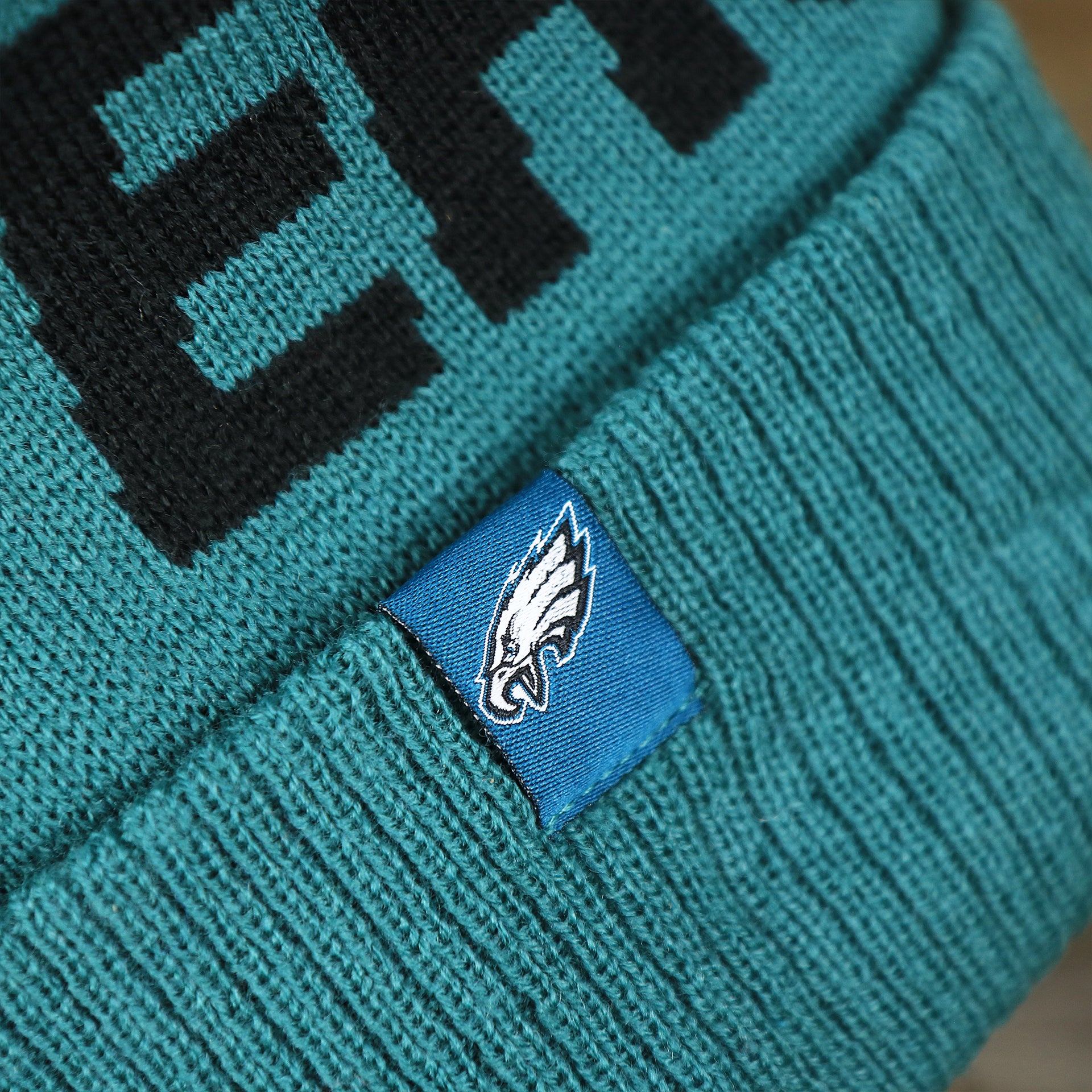 The Eagles Tag on the Philadelphia Eagles On Field Since 1933 Eagles Patch Winter Pom Pom Beanie | Midnight Green Winter Beanie