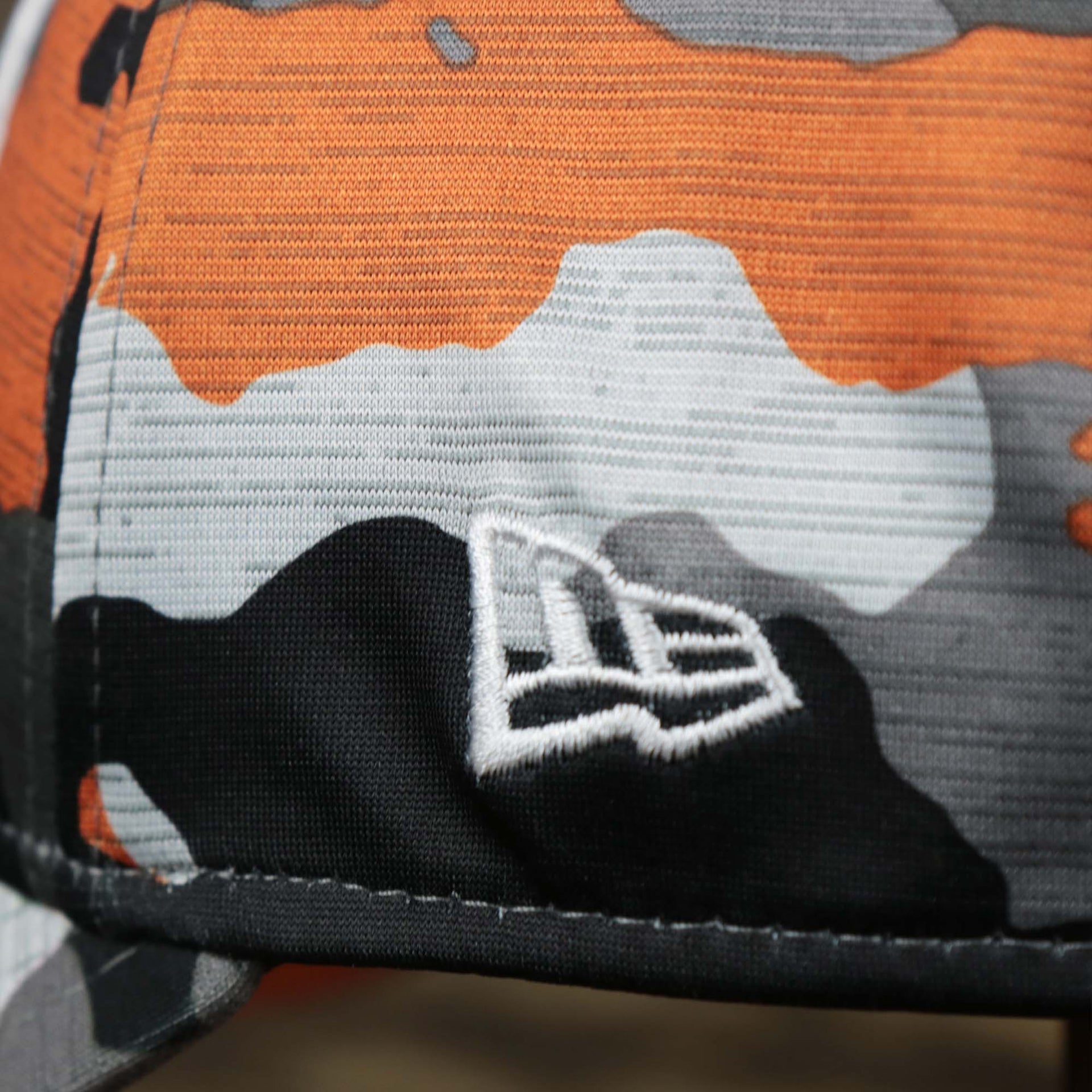 The New Era logo on the Throwback Tampa Bay Buccaneers OnField NFL Summer Training 2022 39Thirty Camo FlexFit Cap | New Era Orange