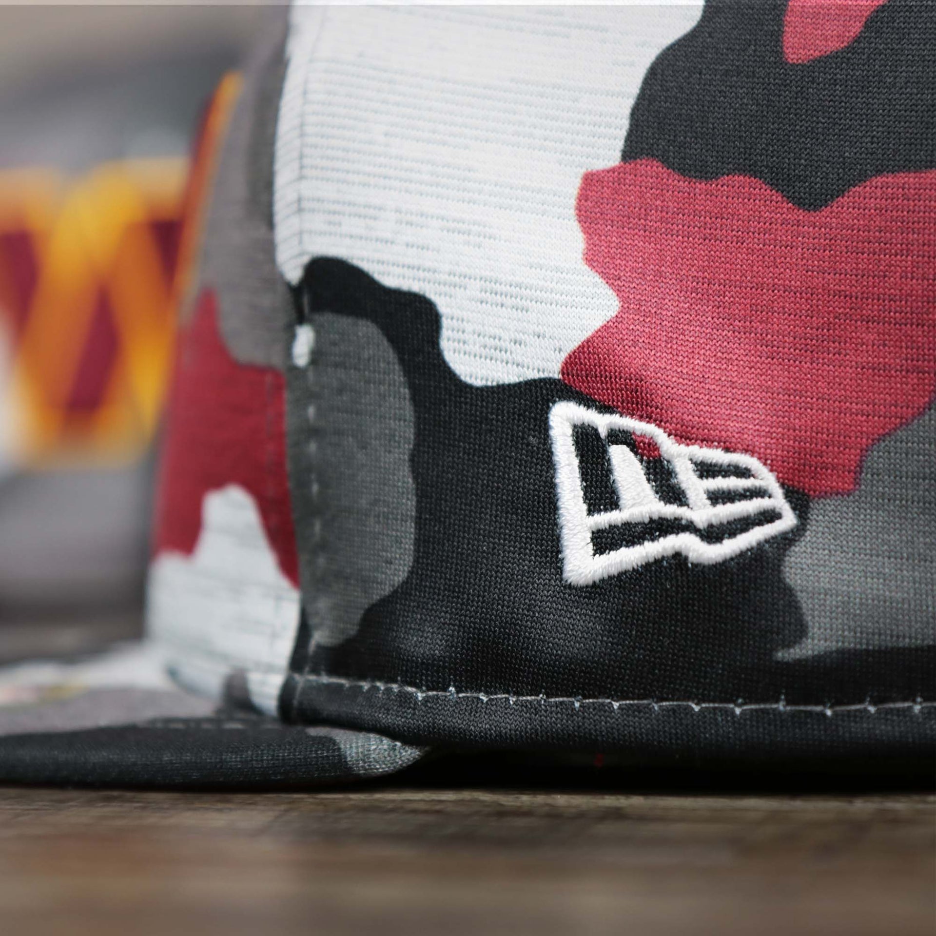 A close up of the New Era Logo on the Washington Commanders NFL OnField Summer Training 2022 Camo 9Fifty Snapback | Burgundy Camo 9Fifty