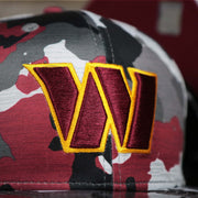 The Commanders Logo on the Washington Commanders NFL OnField Summer Training 2022 Camo 9Fifty Snapback | Burgundy Camo 9Fifty