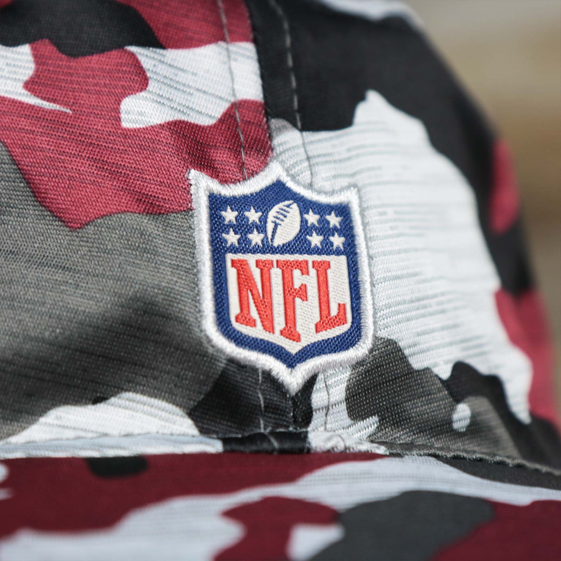 The NFl Logo on the Washington Commanders NFL Summer Training Camp 2022 Camo Bucket Hat | Burgundy Bucket Hat
