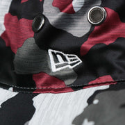 The New Era logo on the Washington Commanders NFL Summer Training Camp 2022 Camo Bucket Hat | Burgundy Bucket Hat