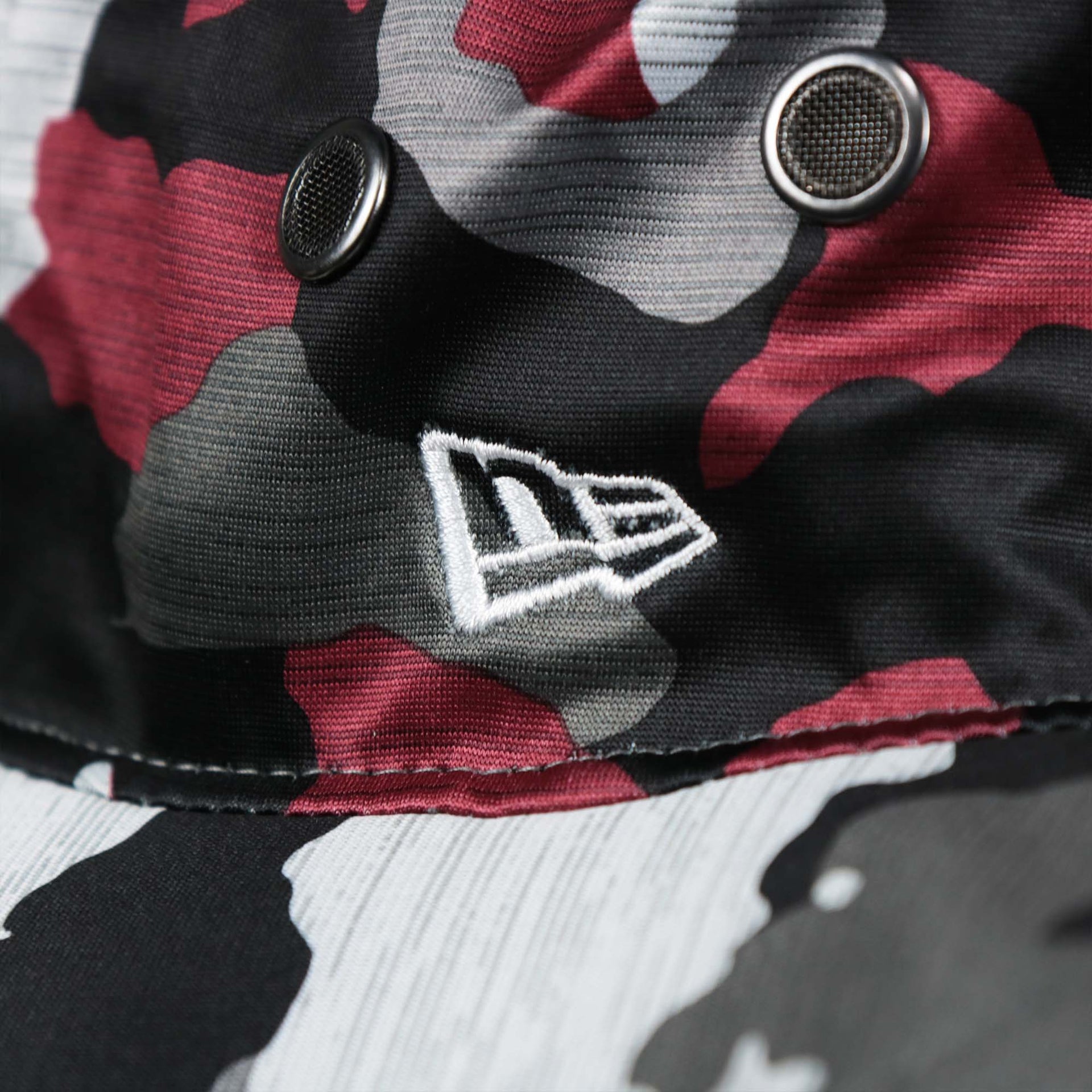 The New Era logo on the Washington Commanders NFL Summer Training Camp 2022 Camo Bucket Hat | Burgundy Bucket Hat