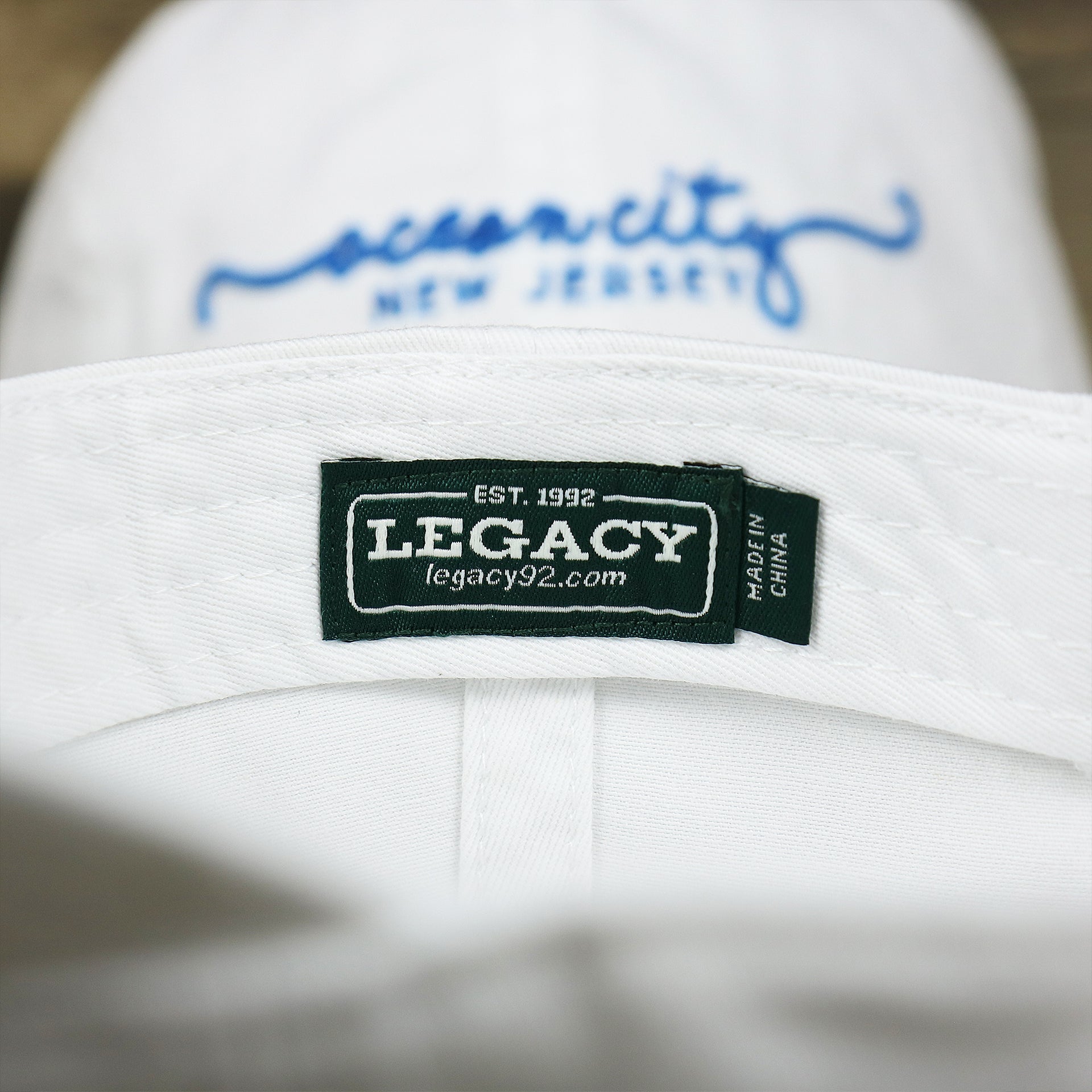 The Legacy tag on the OCNJ New Jersey Ocean City Cursive Wordmark Dad Hat | White Dad Hat 