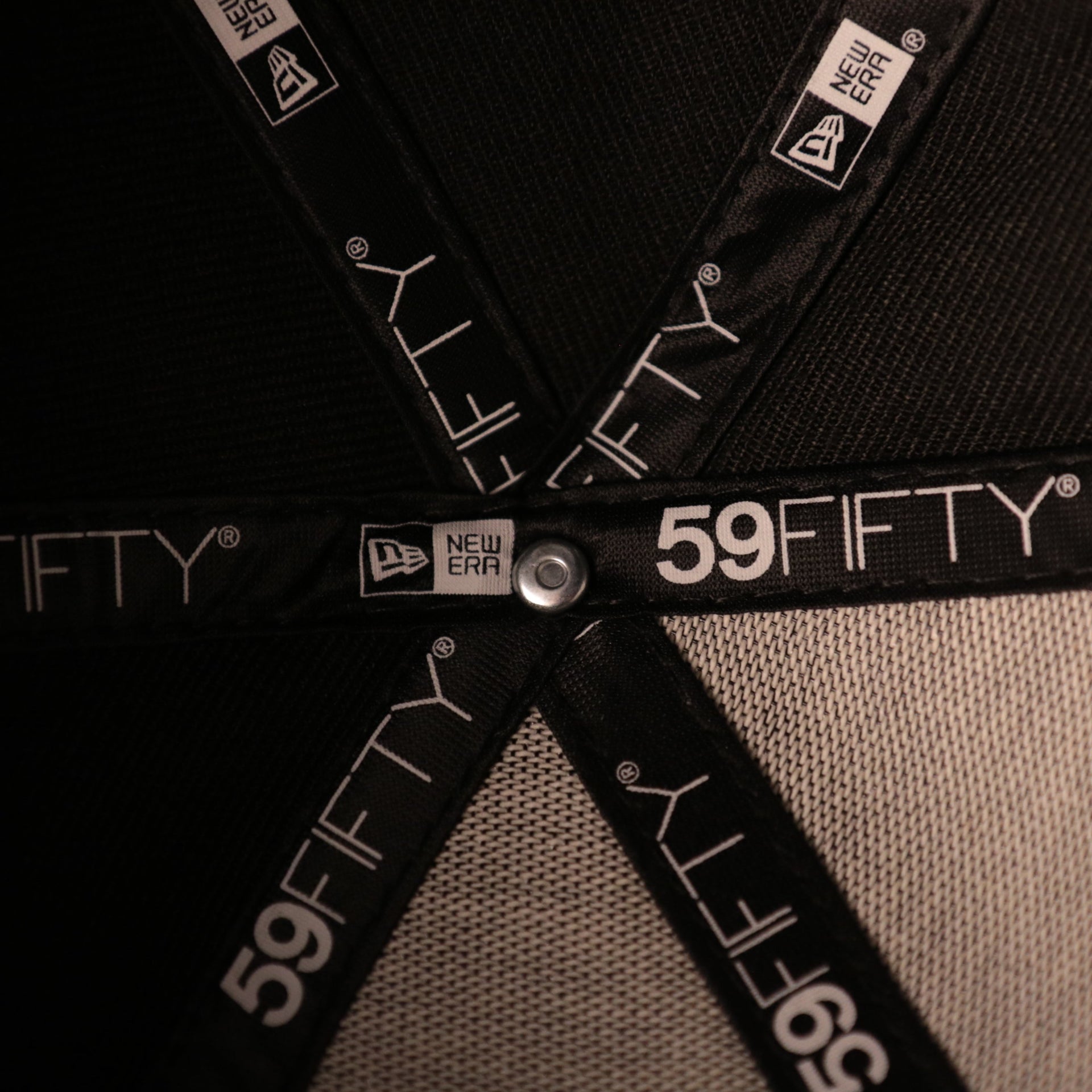 The inside of the black on black fitted cap crown with the New Era 59fifty logo inside it.