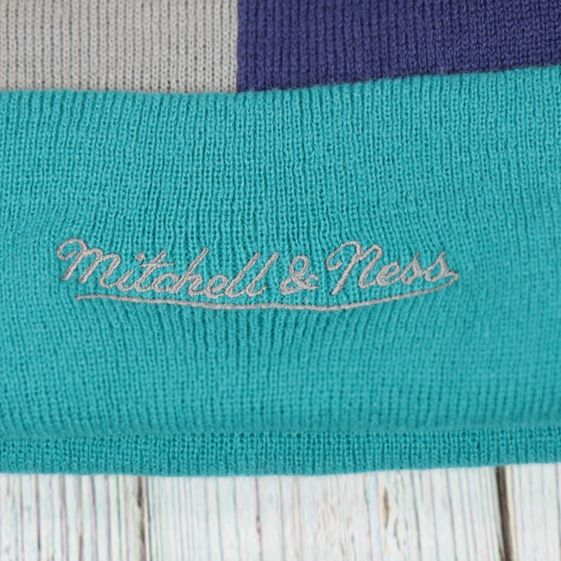 mitchell and ness logo on the Charlotte Hornets Cuffed Logo Split Beanie With Black Pom Pom | Teal, White, And Black Beanie