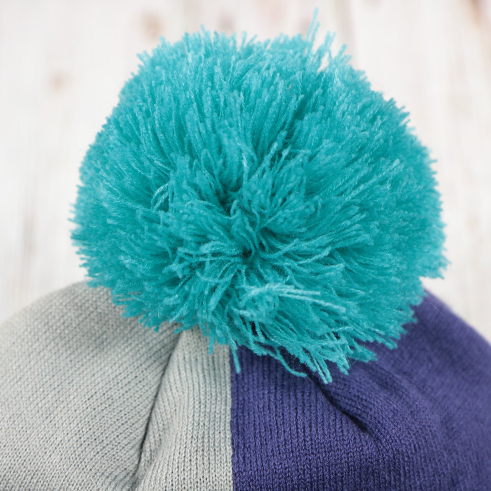 teal pom of the Charlotte Hornets Cuffed Logo Split Beanie With Black Pom Pom | Teal, White, And Black Beanie