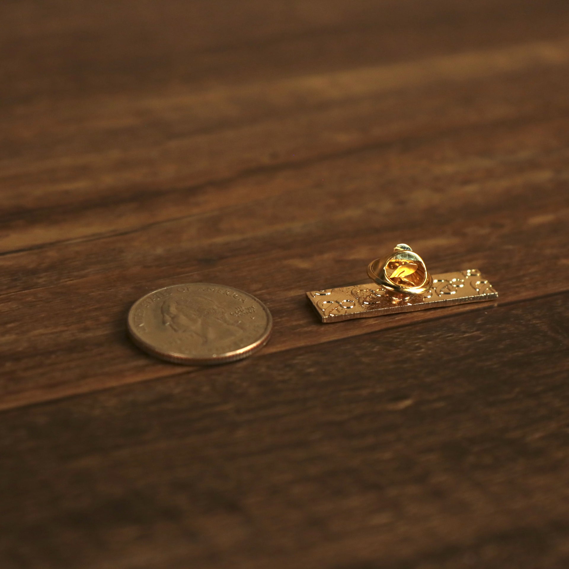 The backside of the New York Shea Station Willets Point Fitted Cap Pin | Enamel Pin For Hat compared to a quarter