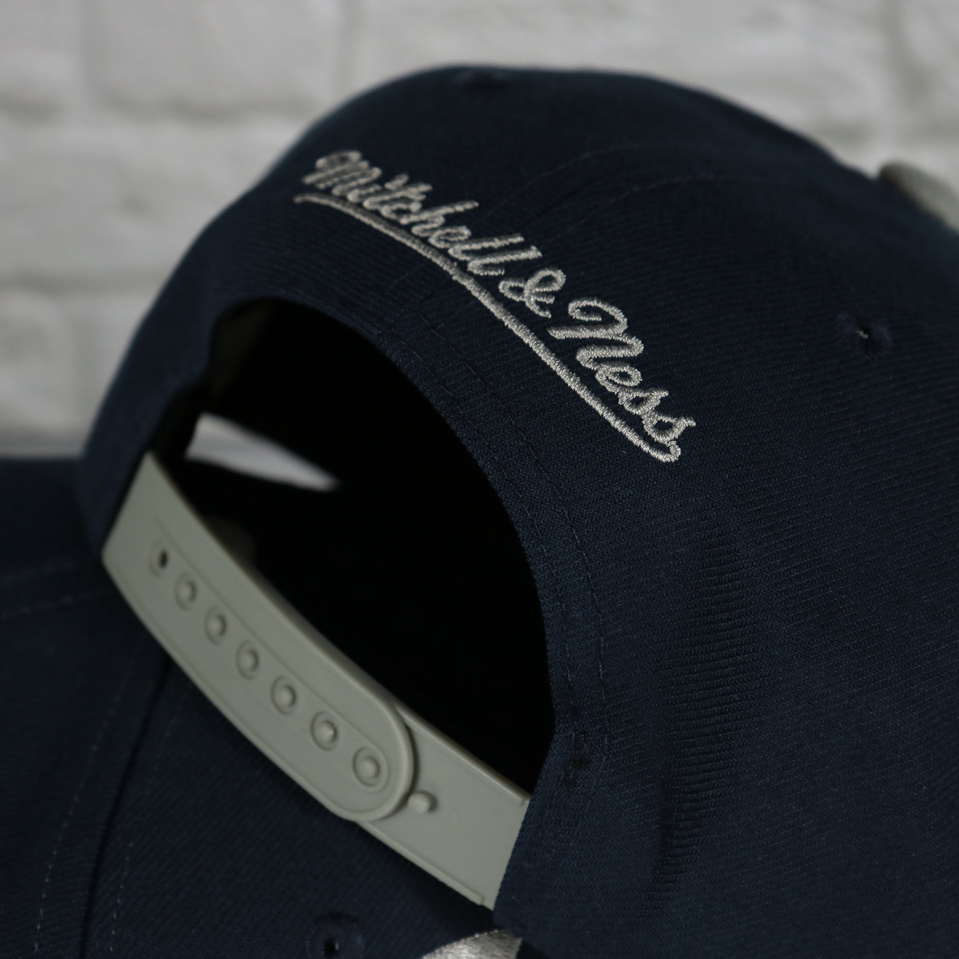 mitchell and ness logo on the Georgetown University Hoyas Vintage Retro Sharktooth Mitchell and Ness Snapback Hat | Gray/Navy Blue