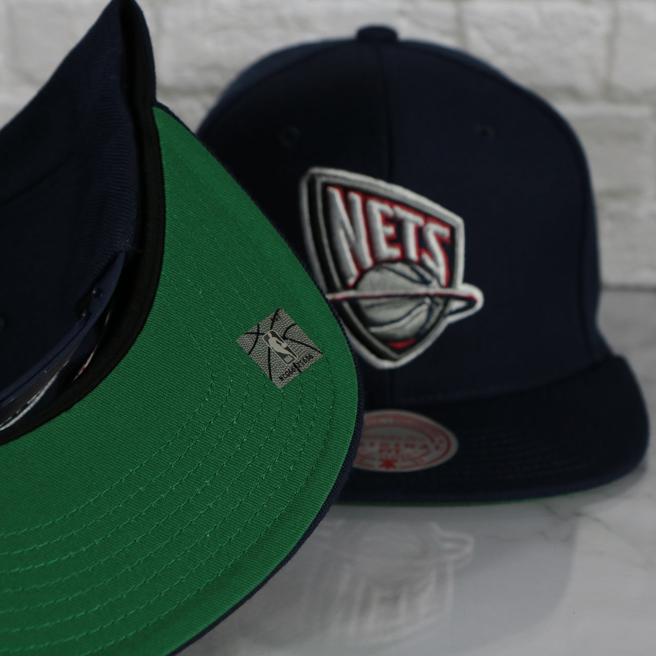 green under visor on the New Jersey Nets Vintage Retro NBA Team Ground 2.0 Mitchell and Ness Snapback Hat | Navy Blue