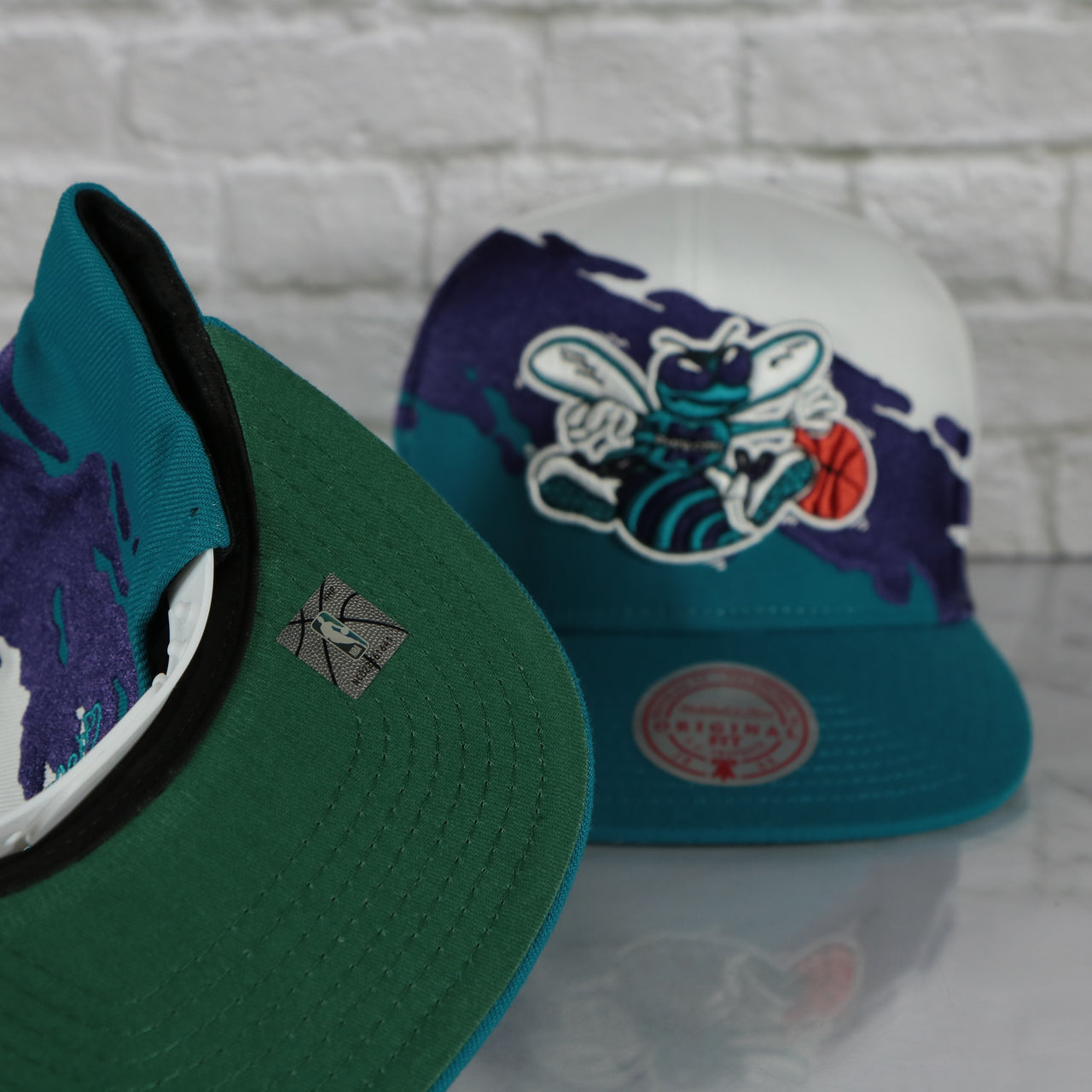 green under visor on the Charlotte Hornets Vintage Retro NBA Paintbrush Mitchell and Ness Snapback Hat | Purple/White/Teal