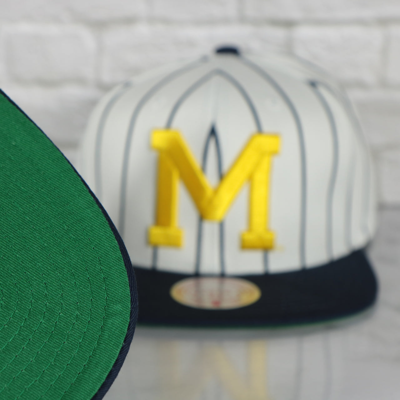 green under visor on the University of Michigan Wolverines Vintage Pinstripe Baseball Hat | Retro Mitchell and Ness White Pinstripe Snapback Hat