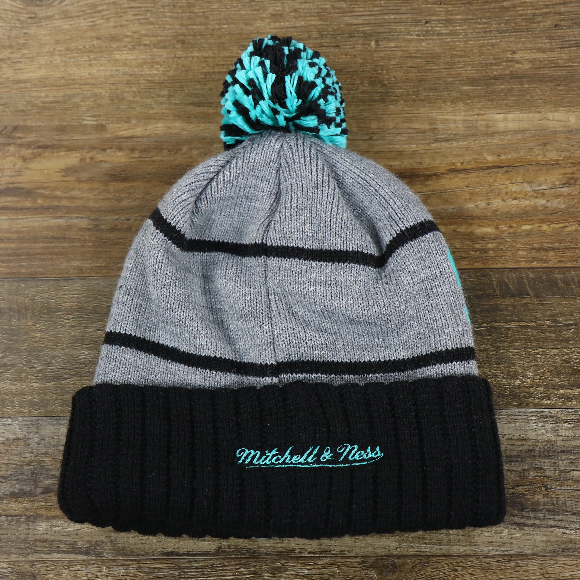 The backside of the Retro San Antonio Spurs Striped Wordmark Cuffed Pom Pom Beanie | Gray And Black Winter Beanie