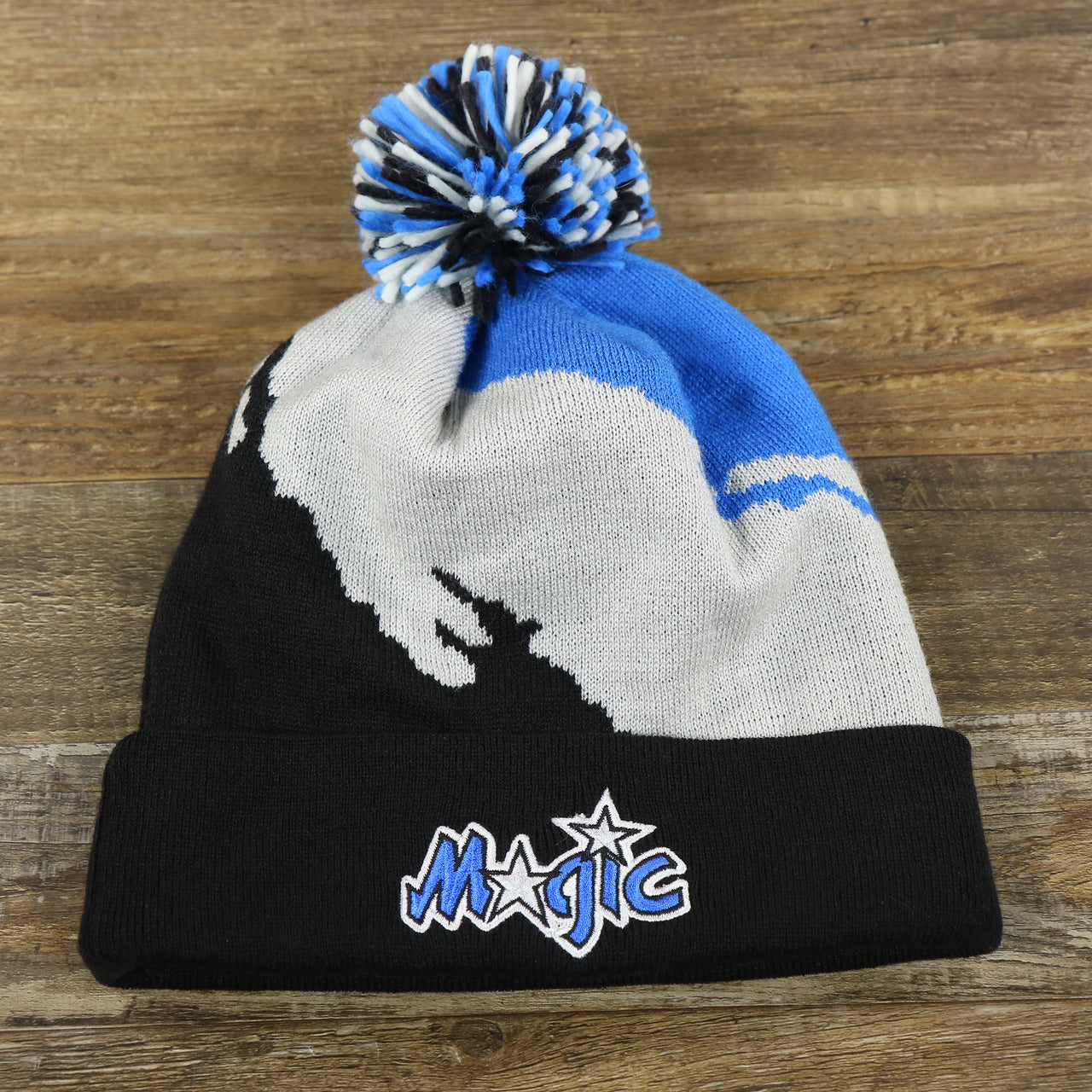 The front of the Orlando Magics Paint Brush Cuffed Winter Beanie With Pom Pom | Black, Gray, And Blue Winter Beanie