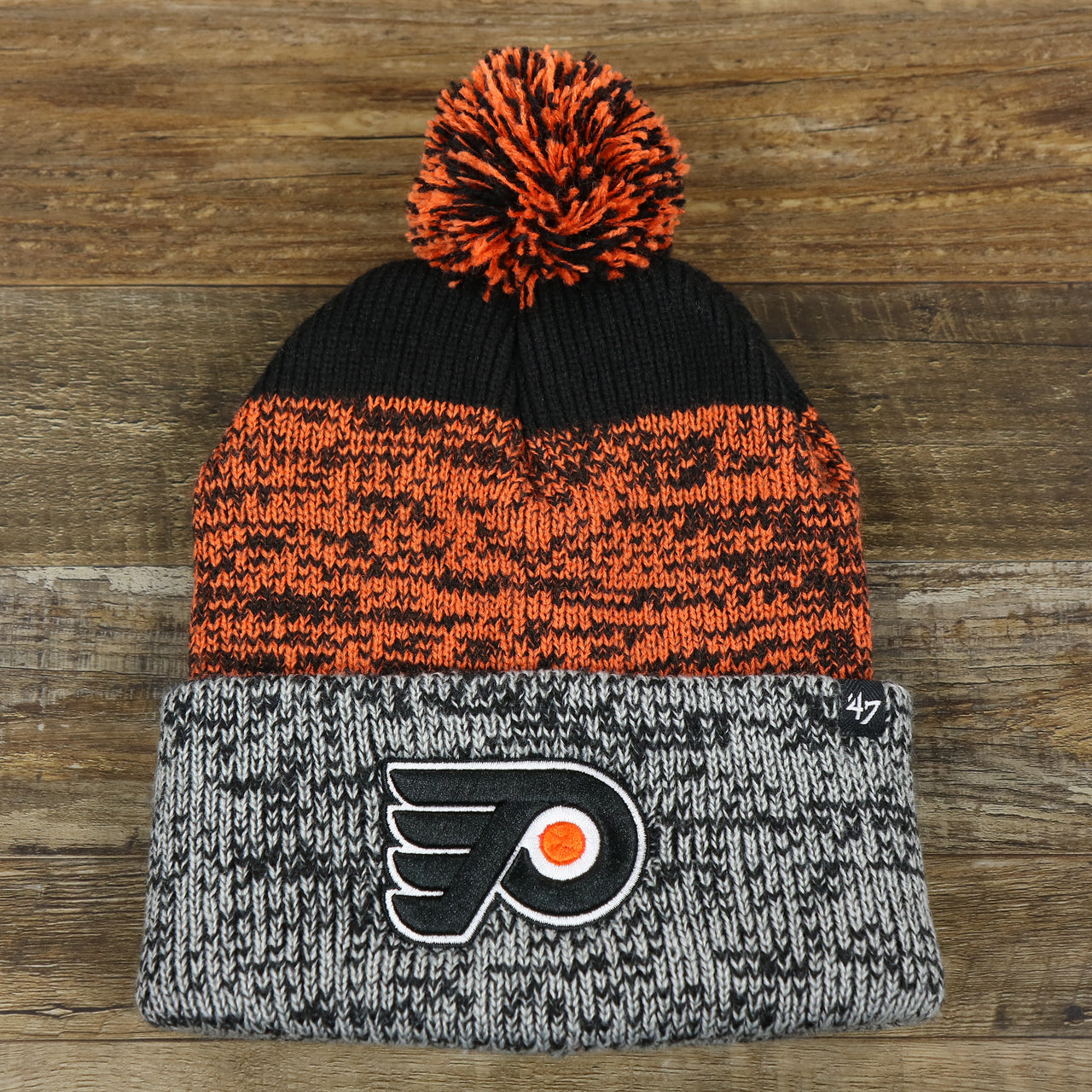 The front of the Philadelphia Flyers Static Knit Cuffed Winter Beanie With Pom Pom | Black, Orange, And Gray Beanie