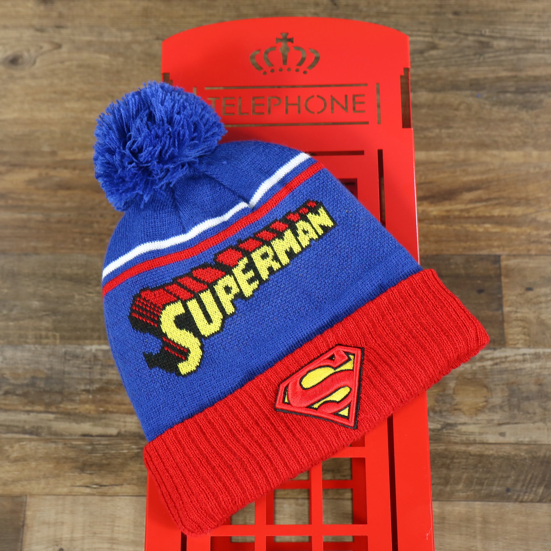 The DC Comics Superman S-Shield Logo Superman Wordmark Striped Beanie With Blue Pom Pom | Blue And Red Winter Beanie