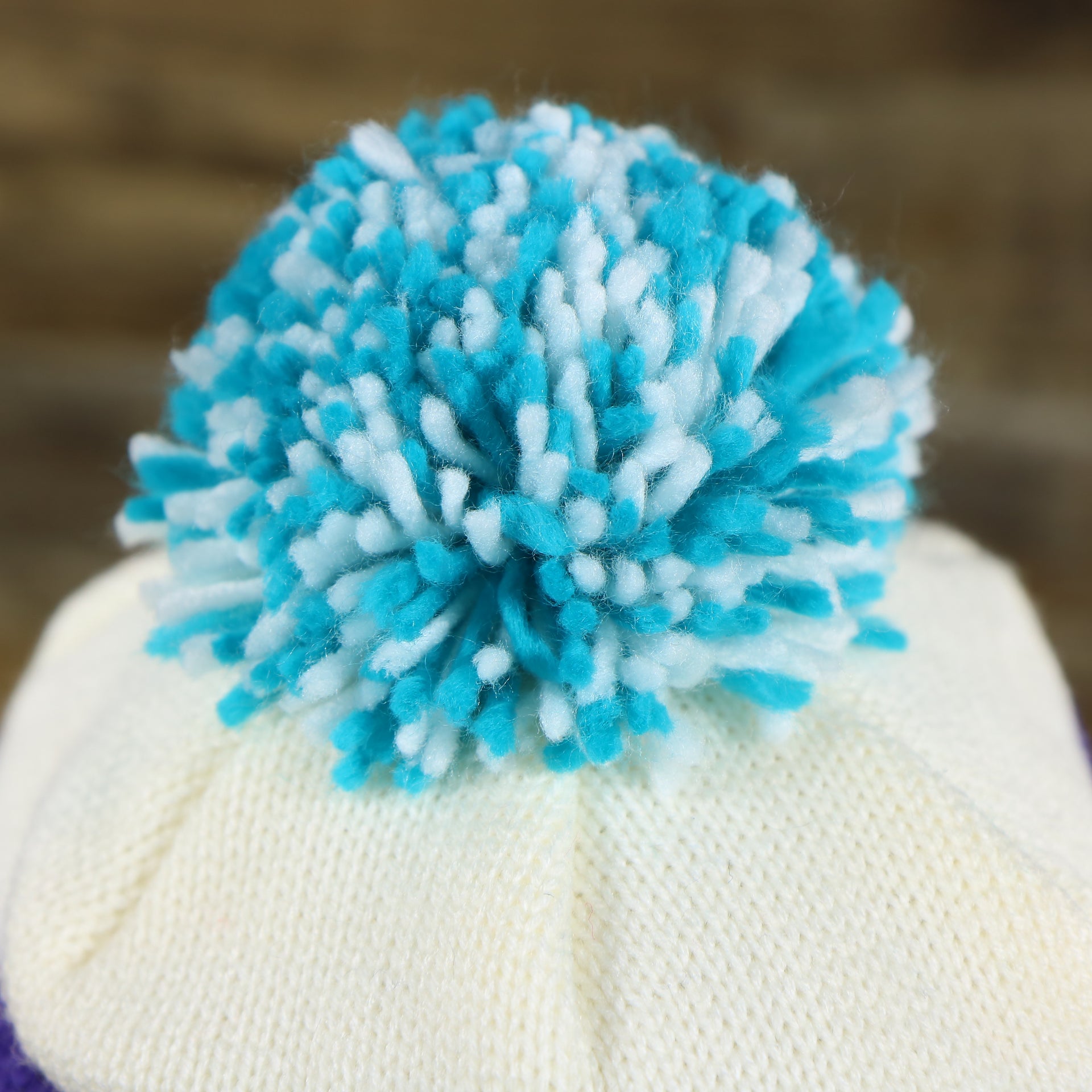 The Pom Pom on the Charlotte Hornets Cursive Wordmark Teal Blue Cuff Pom Pom Winter Beanie | Teal Blue Striped Winter Beanie