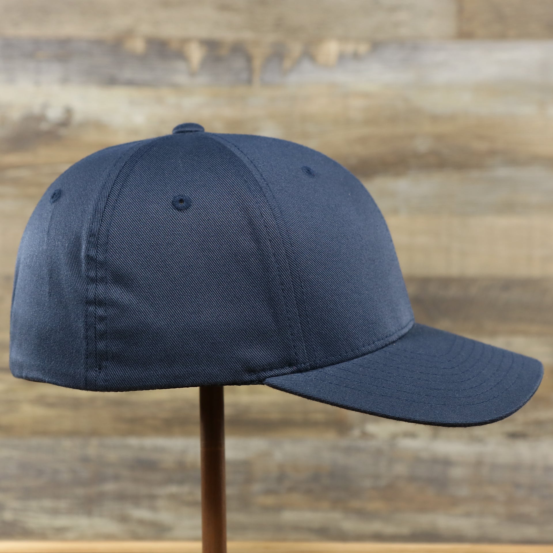 The wearer's right on the Jet Black Bent Brim Silver Bottom Blank FlexFit Cap | Black Flex Cap