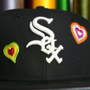 The White Sox Logo on the Chicago White Sox All Over Embroidered Chain Stitch Heart Pink Bottom 59Fifty Fitted Cap | Black 59Fifty Cap