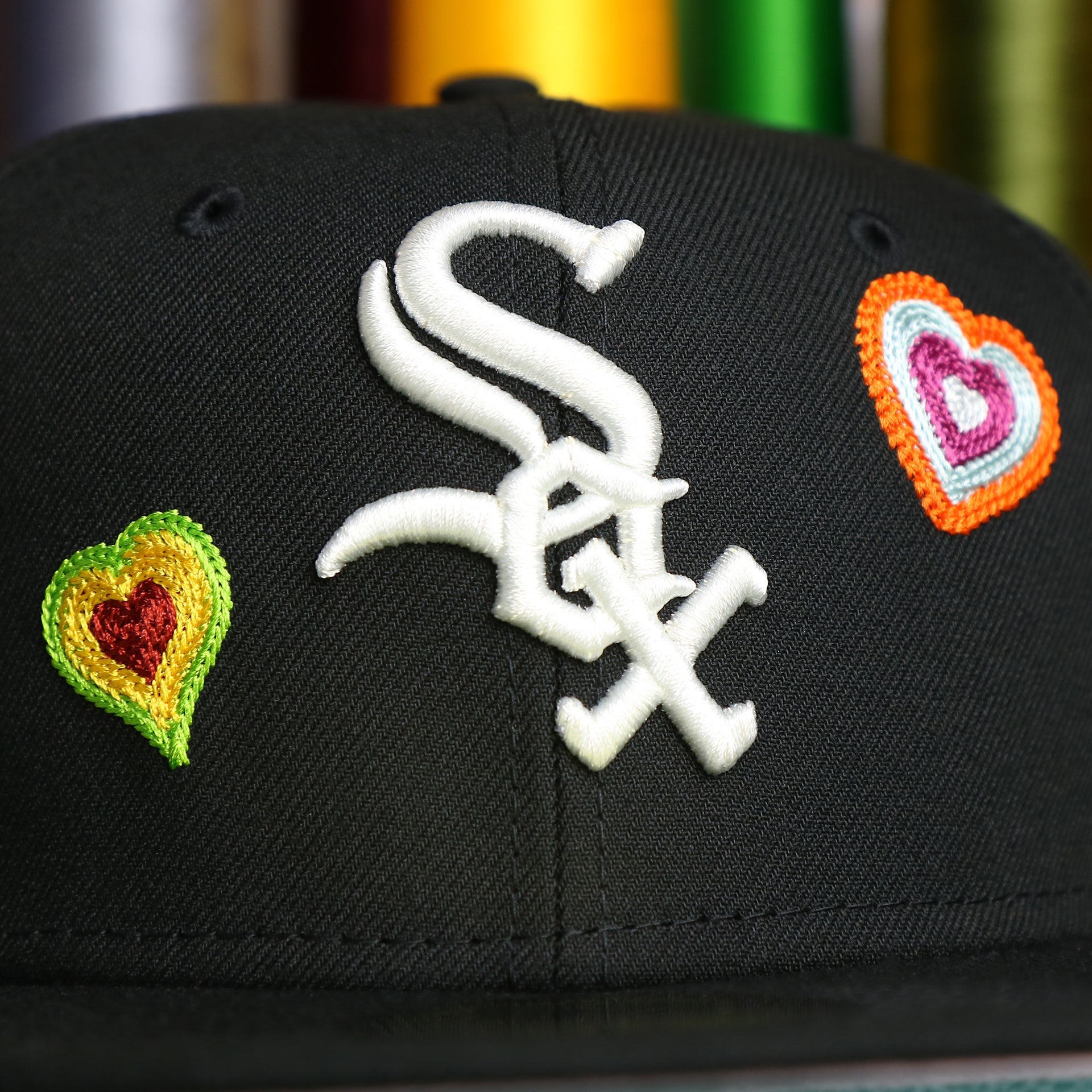 The White Sox Logo on the Chicago White Sox All Over Embroidered Chain Stitch Heart Pink Bottom 59Fifty Fitted Cap | Black 59Fifty Cap