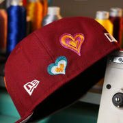 The New Era Logo on the Cooperstown Philadelphia Phillies All Over Embroidered Chain Stitch Heart Pink Bottom 59Fifty Fitted Cap | Maroon 59Fifty Cap