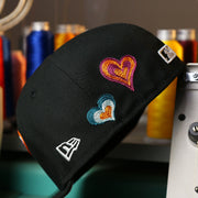 The wearer's left of the Chicago White Sox All Over Embroidered Chain Stitch Heart Pink Bottom 59Fifty Fitted Cap | Black 59Fifty Cap