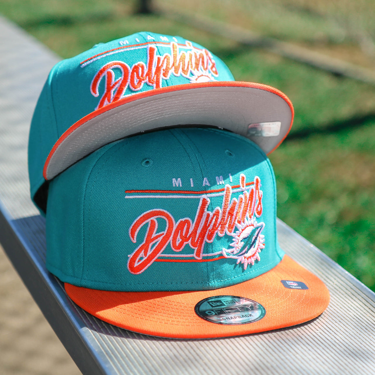 The front of the Miami Dolphins Team Script Gray Bottom 9Fifty Snapback | Aqua and Orange Snap Cap