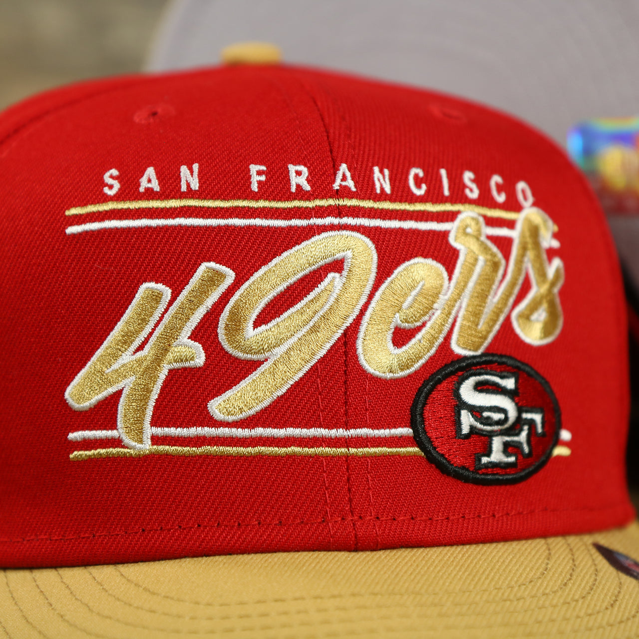 49ers logo on the San Francisco 49ers Team Script College Bar 9Fifty Snapback Hat | Red/Tan 49ers 950 Snap Cap