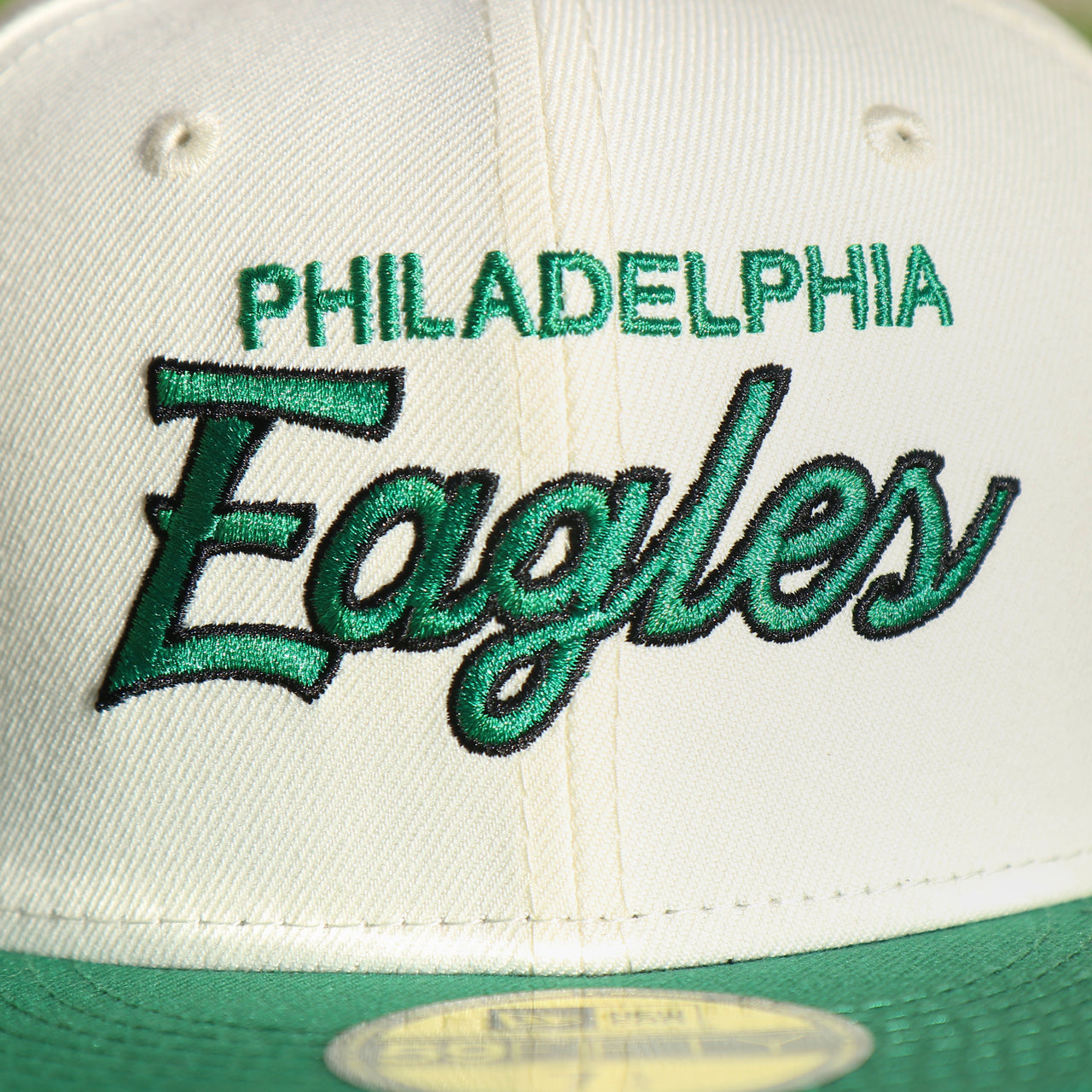 Close up of the front script on the Philadelphia Eagles Throwback Wordmark Jersey Script Cream/Kelly Green Black UV Side Patch 59Fifty Fitted Cap | nohiosafariclub Exclusive