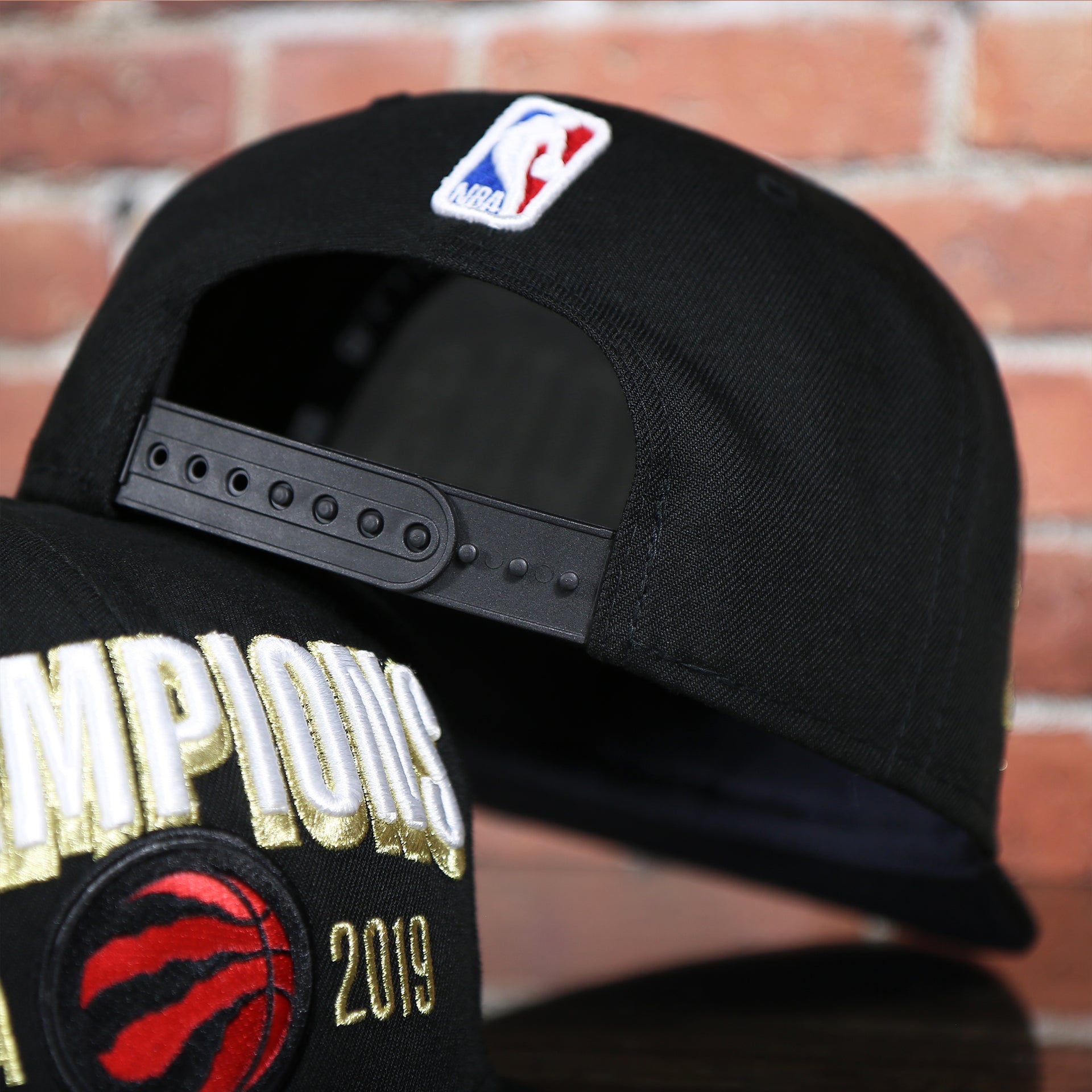 black under visor on the Men's Toronto Raptors New Era Black 2019 NBA Finals On Court Champions Locker Room 9FIFTY Snapback Hat