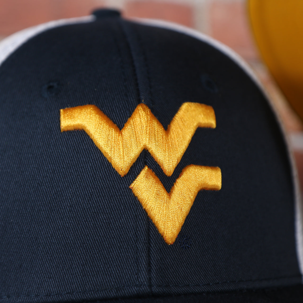 west Virginia log on the front of the West Virginia Mountaineers MVP Yellow Bottom Trucker Cap | Navy/White | OSFM