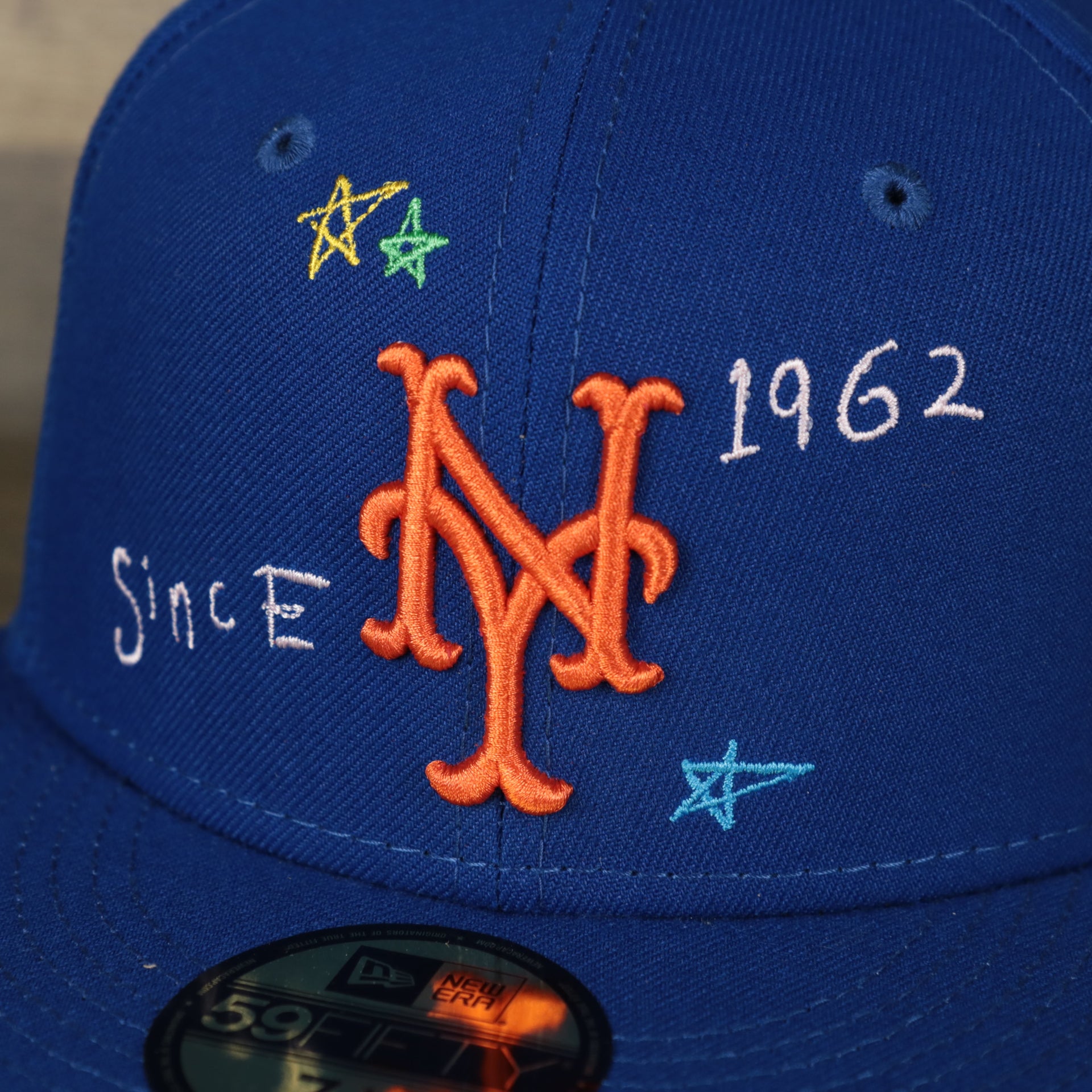 A close up of the Mets logo on the New York Mets “Scribble” Side Patch Gray Bottom 59Fifty Fitted Cap
