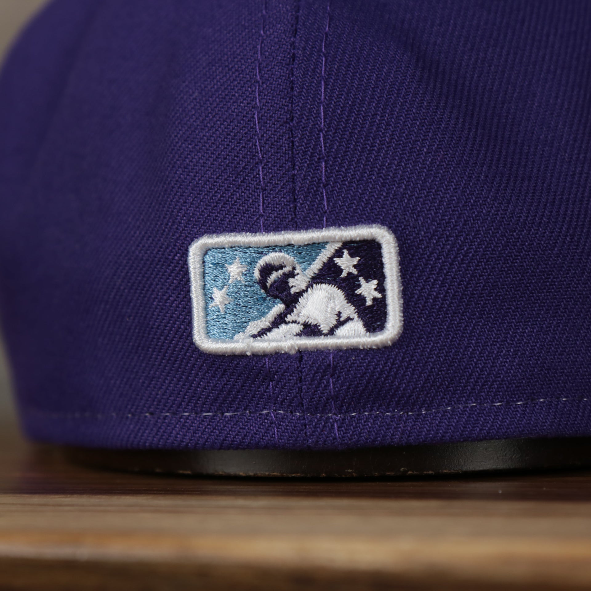 milb logo on the Jersey Shore Blue Claws 2022 Medusas de Jersey Shore Copa de la Diversion On-Field Black Bottom 5950 Fitted Cap | Purple/White