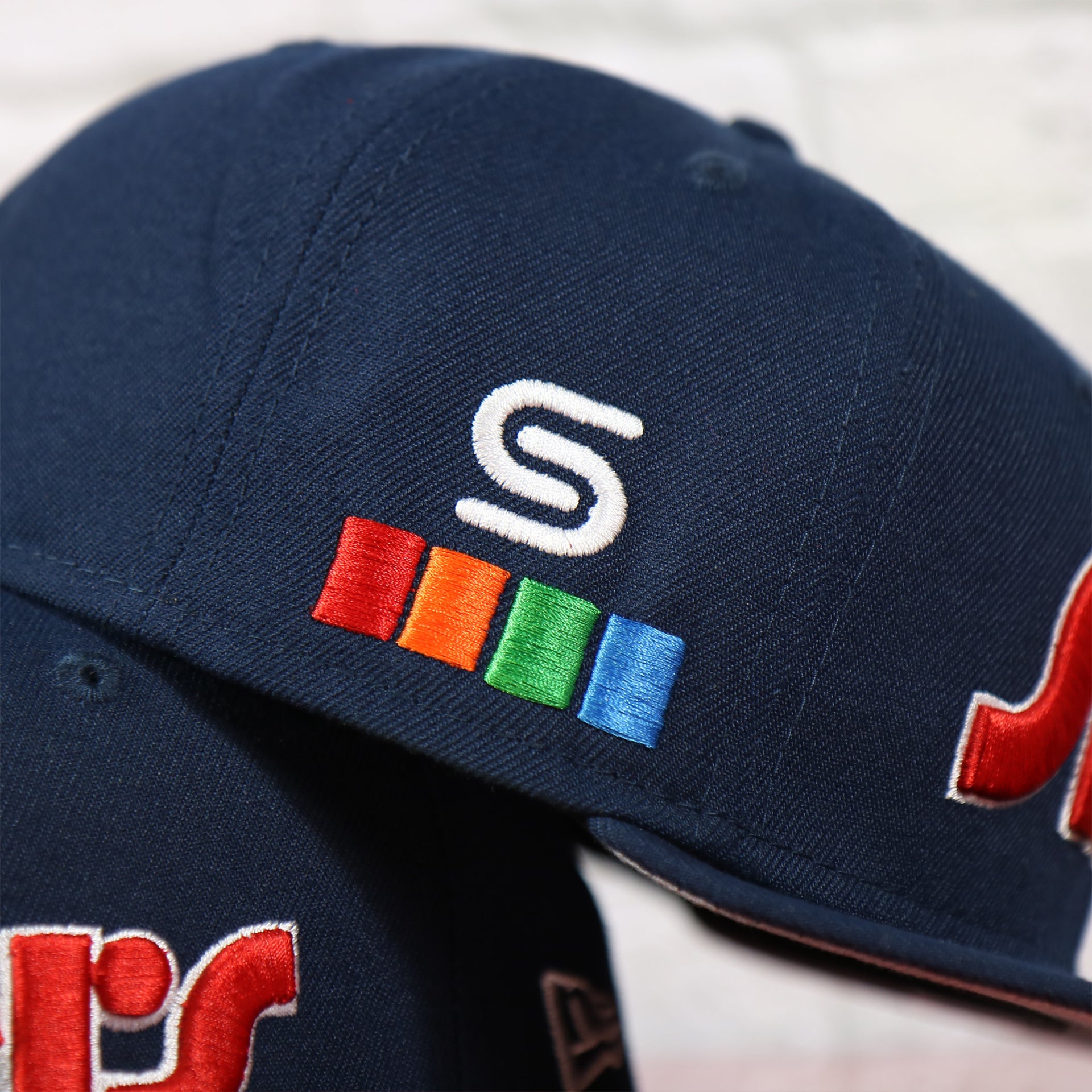 Close up of the spectrum side patch on the Philadelphia 76ers 2022 City Edition Sixers Script Spectrum Side Patch Navy 59Fifty Fitted Cap