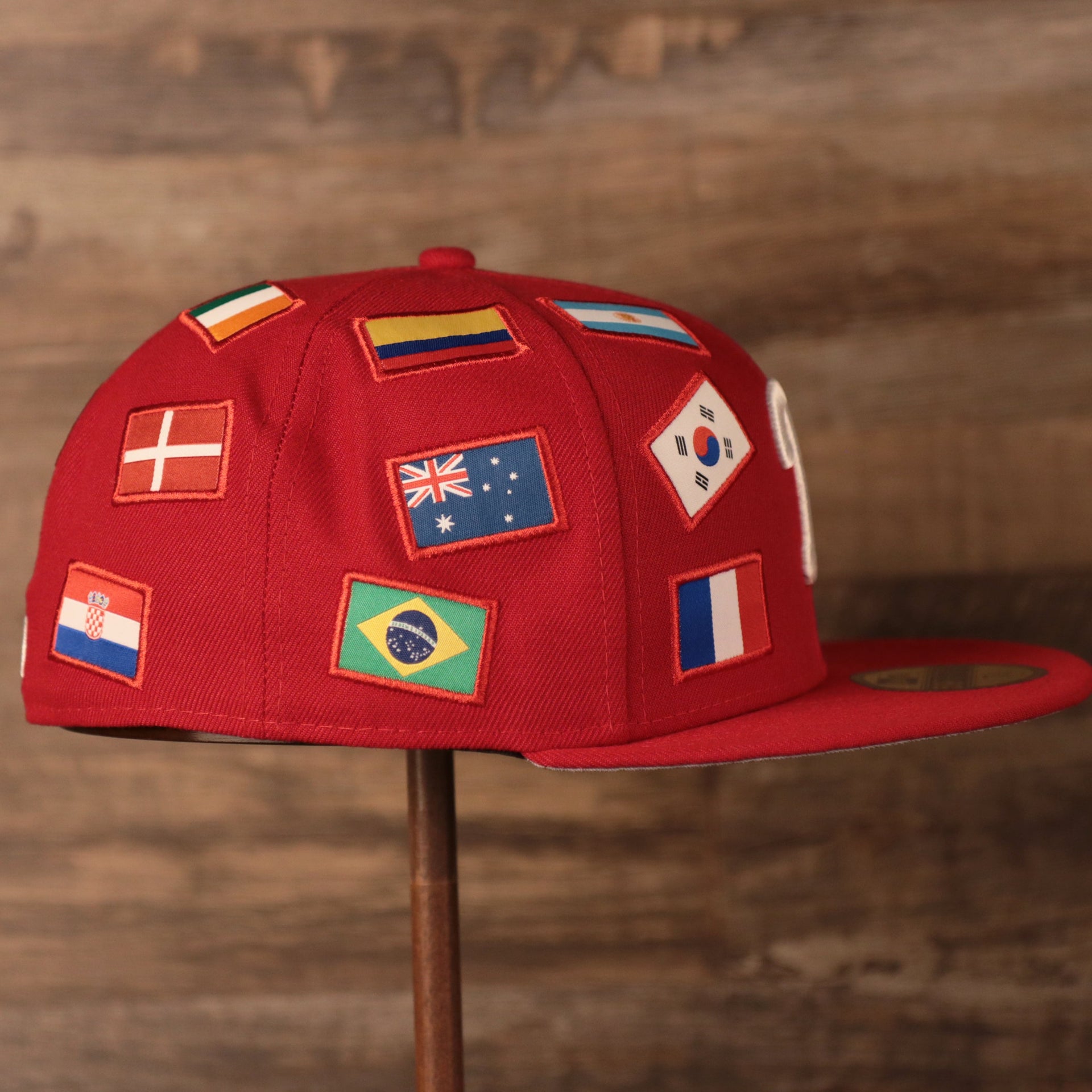 Phillies World Flags Gray Bottom Fitted Cap | Philadelphia Phillies International Flags Red Grey Under Brim Fitted Cap the wearers right side has flags from the countries of Brazil. Australia, and Colombia