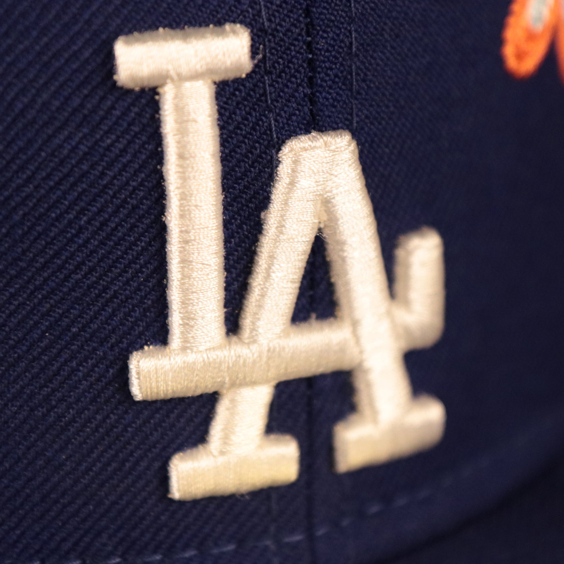 Close up of the Los Angeles Dodgers logo embroidered on the front of the Los Angeles Dodgers All Over Floral Pattern Flower Crotchet Side Patch Pink Bottom 59Fifty Fitted Cap