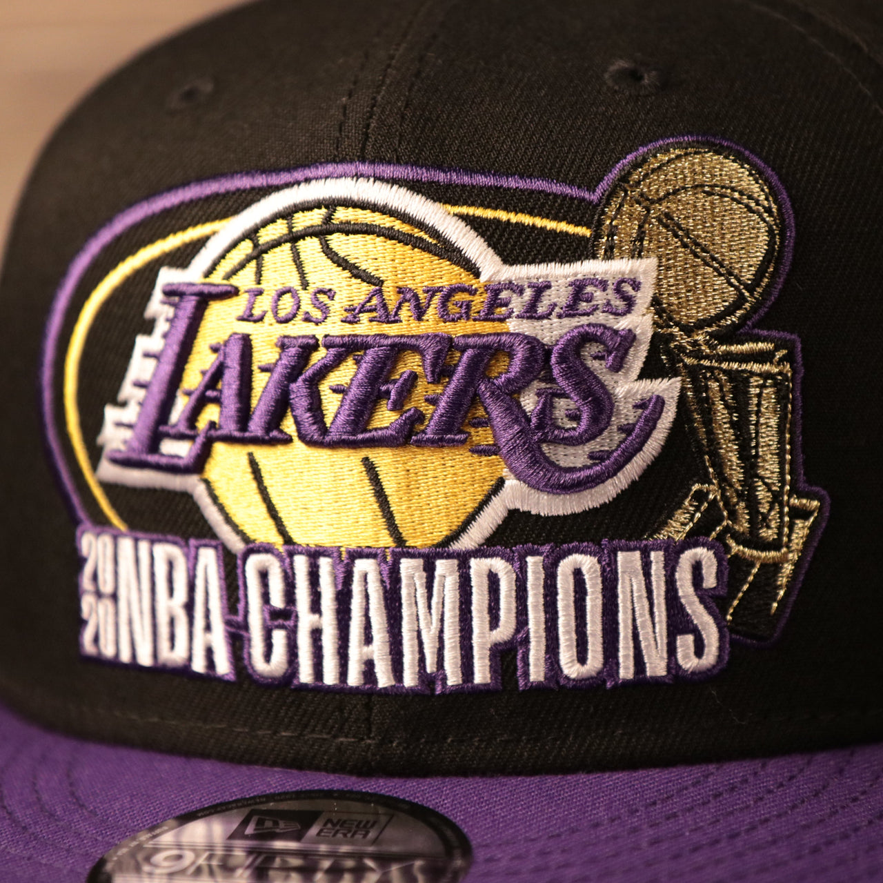 The logo of the Los Angeles Lakers 2020 champions on the front side of the black/purple 9fifty by New Era.