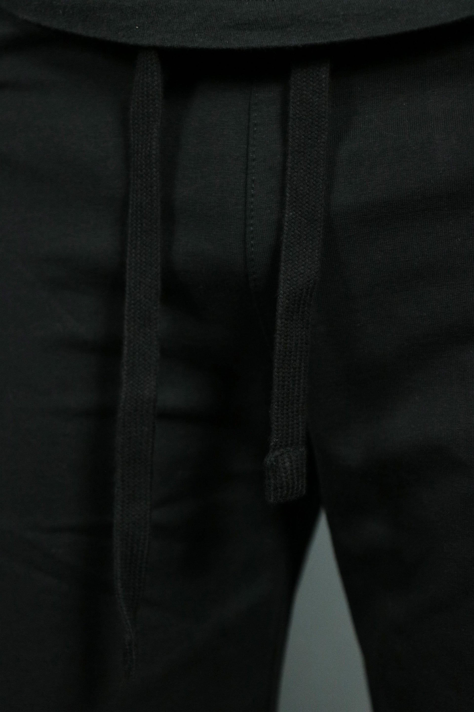The black drawstrings of the black mens terry shorts by Jordan Craig.