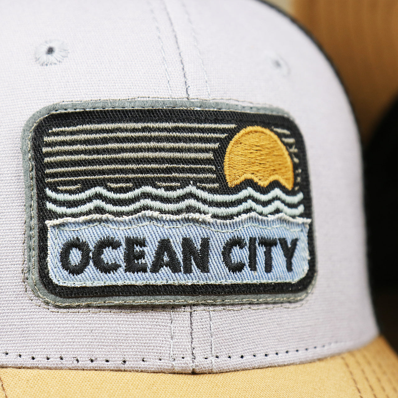 The Ocean City Sunset Patch on the Youth New Jersey Ocean City Sunset Mesh Back Trucker Hat | Gray And Black Mesh Youth Trucker Hat