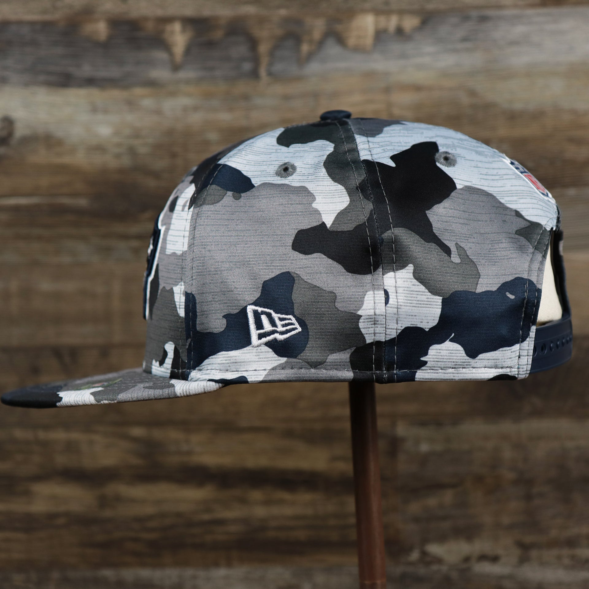 The wearer's left of the New England Patriots NFL OnField Summer Training 2022 Camo 9Fifty Snapback | Navy Blue Camo 9Fifty