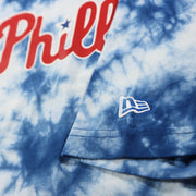 new era logo on the sleeve of the Philadelphia Phillies Current Phillies Wordmark Tie-Dye MLB T-Shirt | Columbia Blue Tie-Dye Tshirt