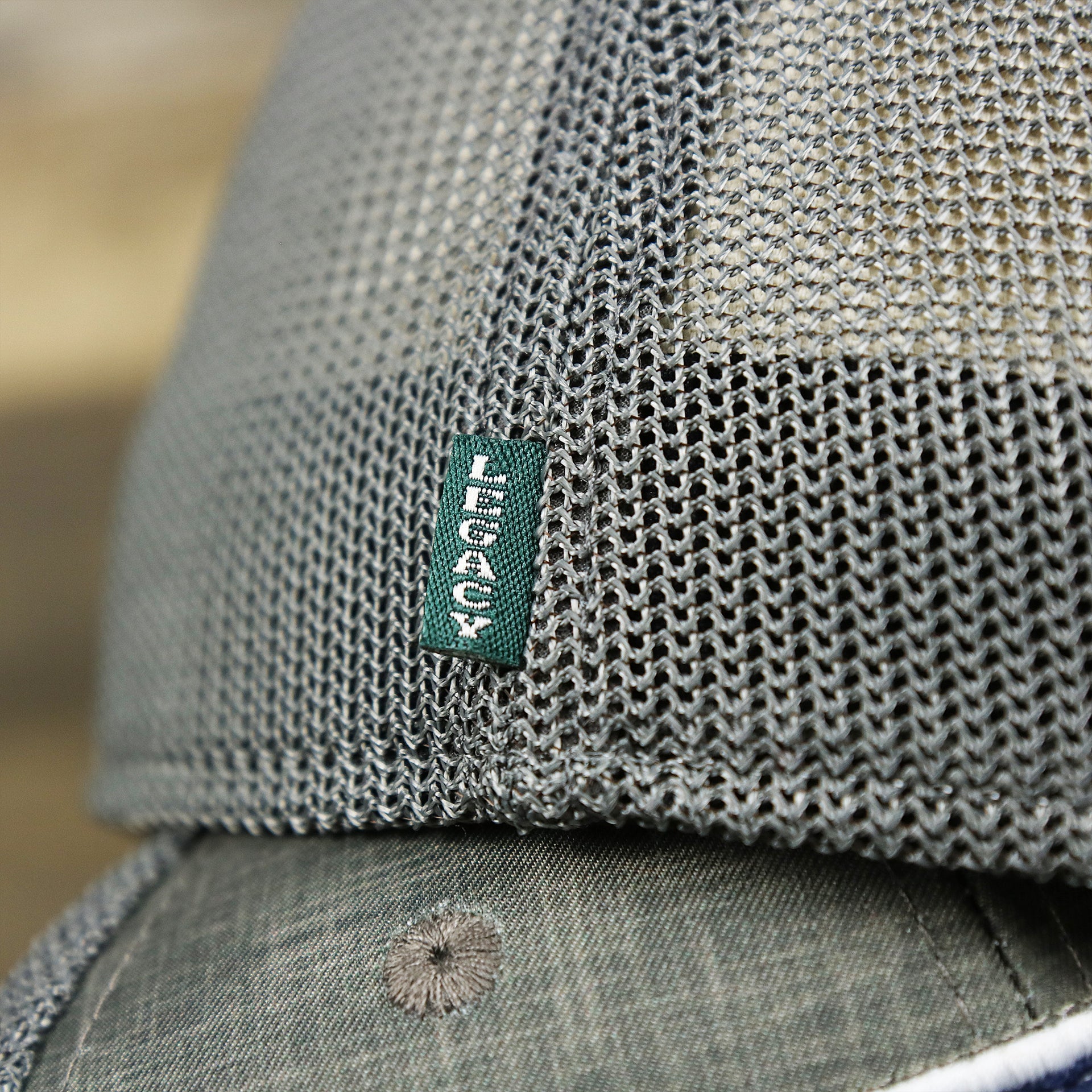 The Green Legacy Tag on the OCNJ Ocean City 1879 Sunset Wave Logo Mesh Stretch FIt Hat | Dark Green And Dark Grey Stretch Fit Hat