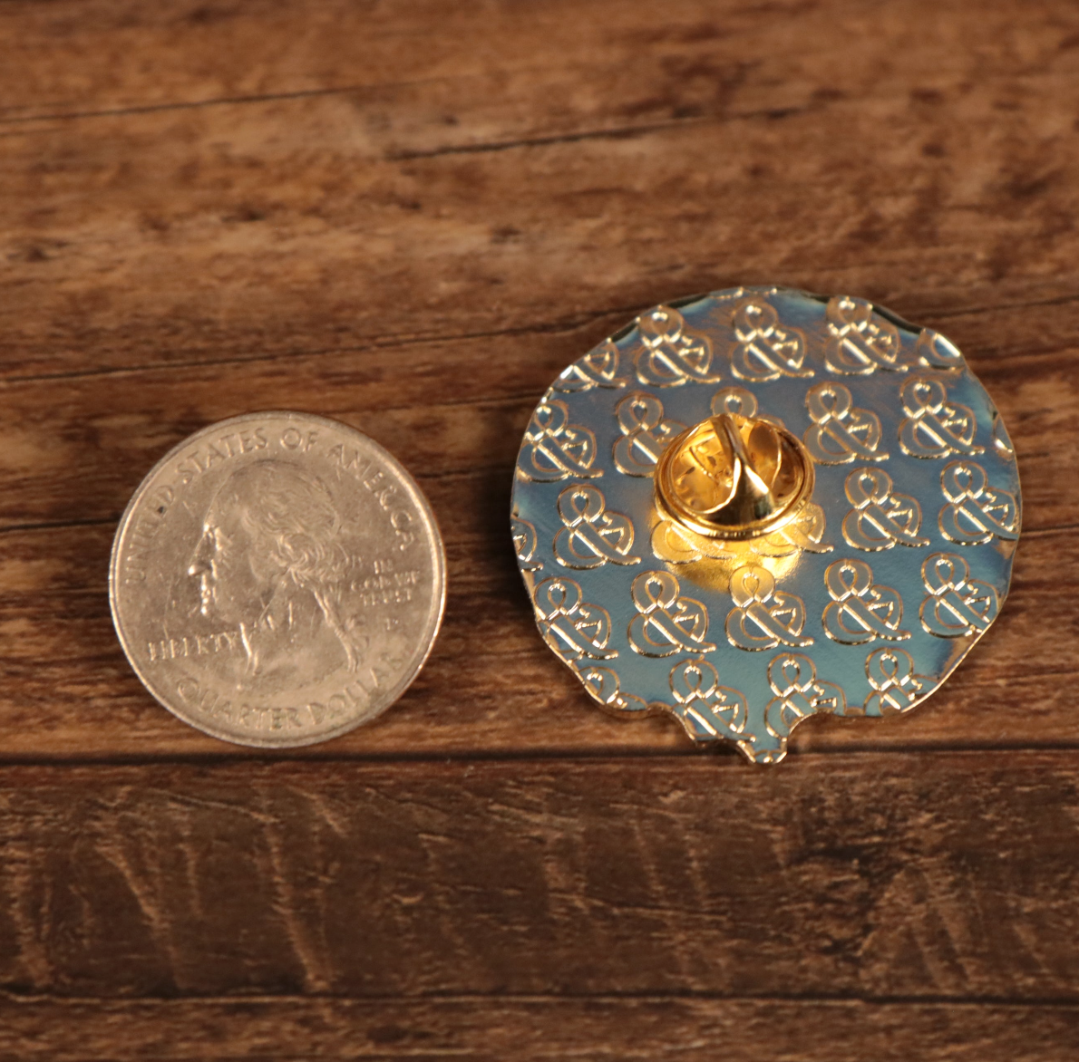 The backside of the New York Bagel Fitted Cap Pin | Enamel Pin For Hat Compared to a Quarter