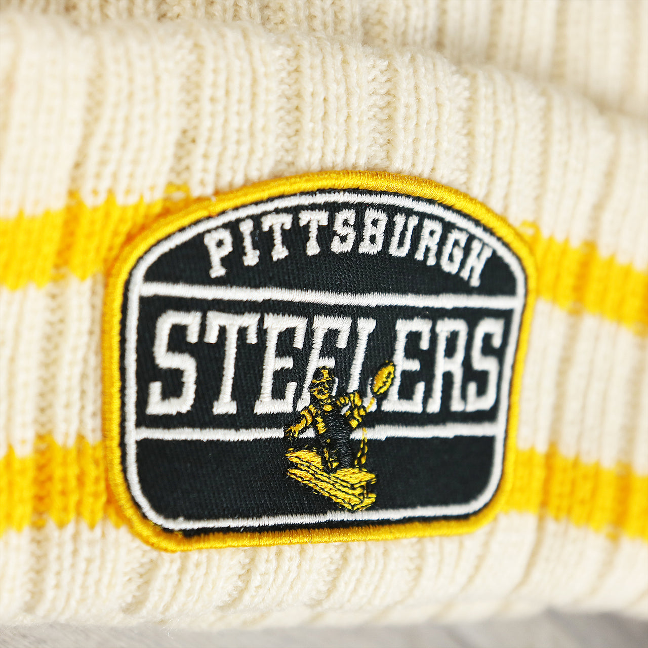 The Steelers Patch on the Throwback Pittsburgh Steelers Legacy 1962 Steelers Patch Pom Pom Beanie | Natural Beanie